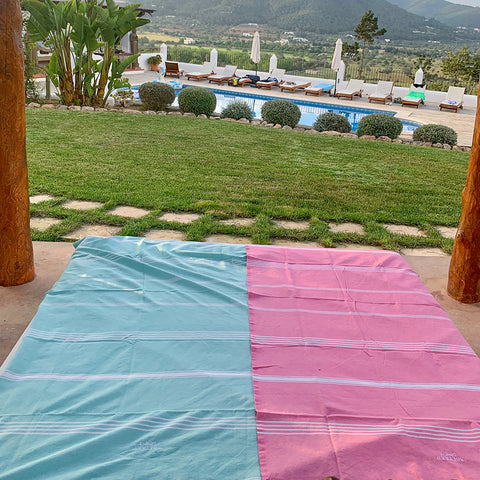 ein aquablaues Strandtuch und eine rosa Fouta für den Pool