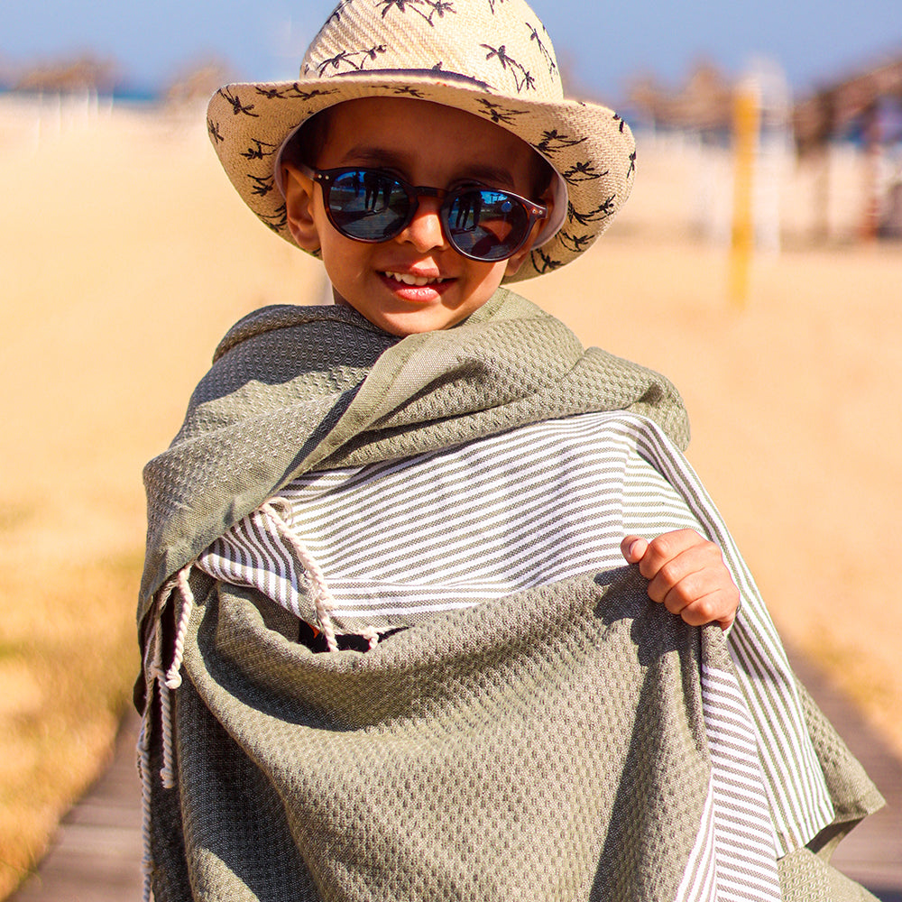 Kleines Kind in grauem hamamtuch fouta am Strand