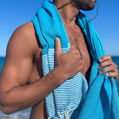 Mann mit blauem Hamamtuch auf den Schultern am Strand