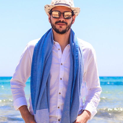 Mann mit Hut und Sonnenbrille in marineblauem Hammamtuch am Strand