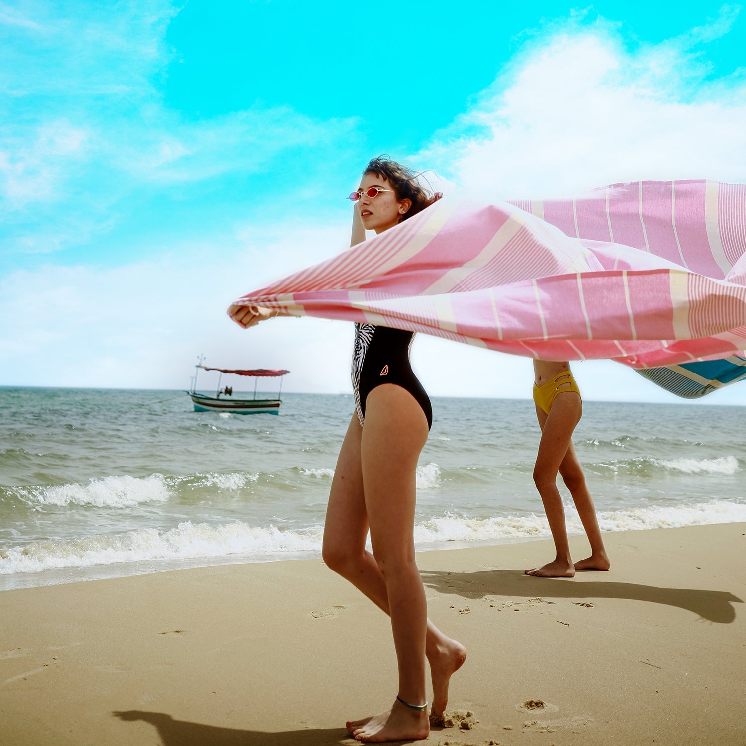 zwei Mädchen am Strand die ein rosa XXL Strandtuch fouta halten