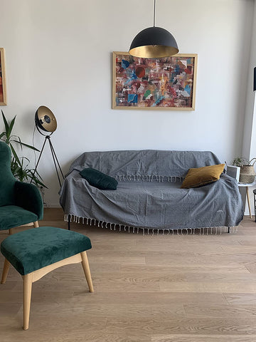 eine dunkelgraue Decke mit Quasten und Kissen auf dem Sofa im Wohnzimmer