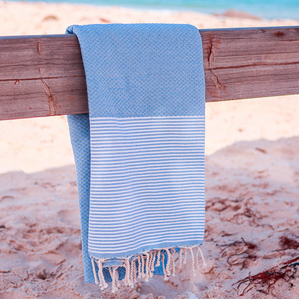 blaues Strandtuch auf einem Stück Holz am Strand aufgehängt