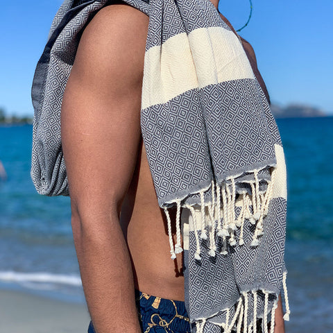 Mann mit grauer Fouta auf den Schultern am Strand