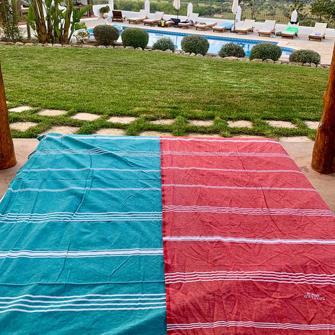 eine hellblaue Fouta und ein rosa Hamamtuch am Pool