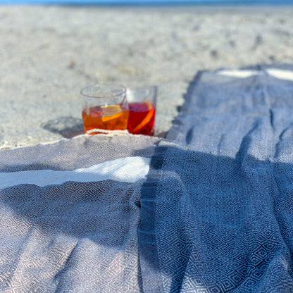 ein hellgraues Strandtuch und ein dunkelgraues Strandtuch auf dem Sand